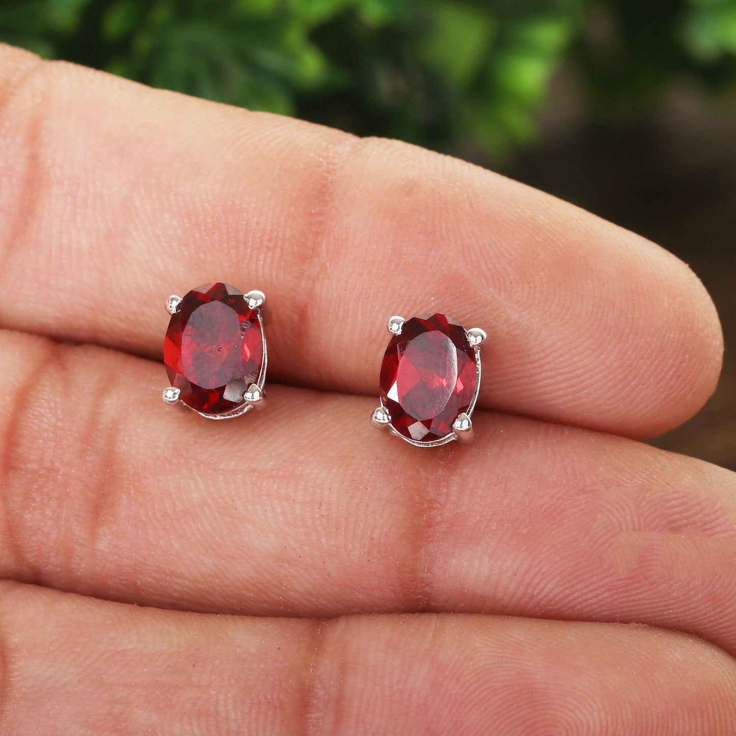 Red garnet earrings worn on ear, oval cut, anniversary gift styling