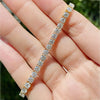 Pattern of round brilliant diamonds along yellow gold tennis bracelet links