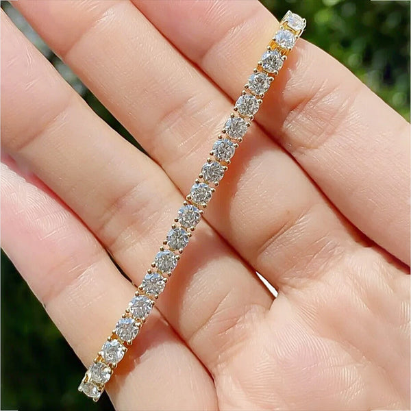 Pattern of round brilliant diamonds along yellow gold tennis bracelet links
